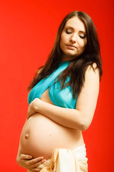 大人の女性が彼女の妊娠中の腹を見せて — ストック写真