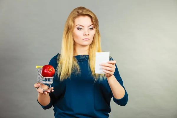 Worried woman holding shopping basket with fruits — Stock Photo, Image