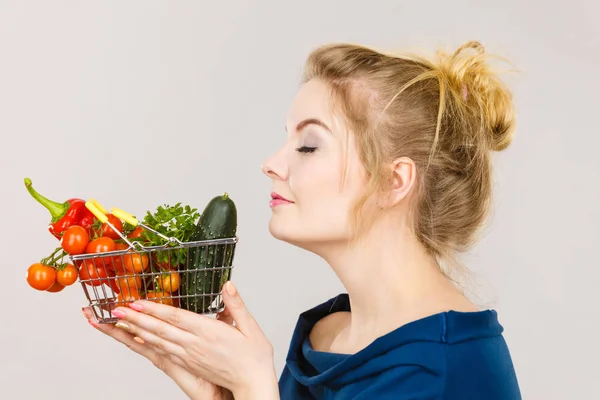 Mulher segura cesta de compras com legumes, cheirando — Fotografia de Stock