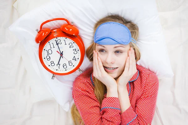 時計を保持しているパジャマを着てショックを受けた女性は寝坊しました。 ロイヤリティフリーのストック画像