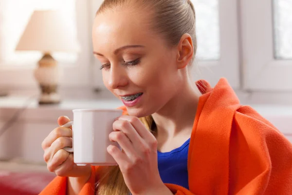 Mujer acostada en un sofá bajo una manta bebiendo té — Foto de Stock