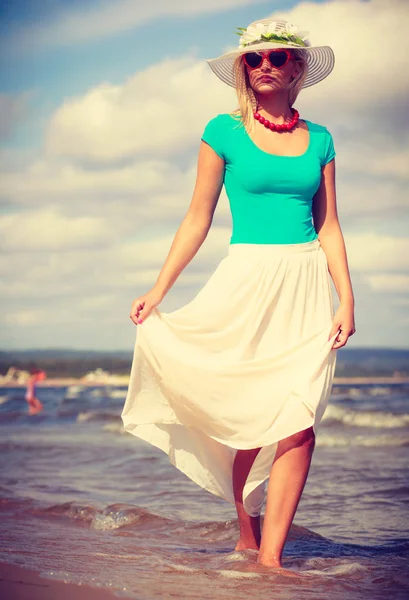 Mujer rubia usando vestido caminando en la playa — Foto de Stock