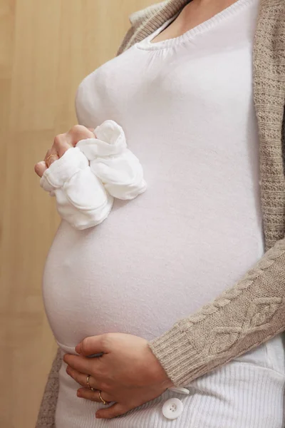 Femme enceinte tenant de petites chaussures de bébé — Photo