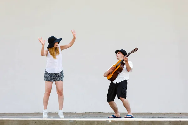 Мужчина играет на гитаре, женщина веселится — стоковое фото