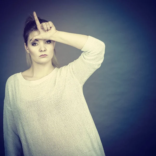 Frau zeigt Verlierer-Geste mit l auf der Stirn — Stockfoto