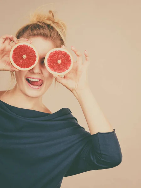 Kobieta trzyma owoców grejpfruta, połowę na oczy — Zdjęcie stockowe