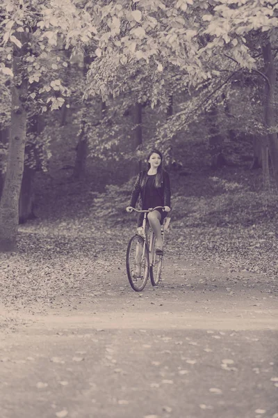 Roodharige dame fietsen in park. — Stockfoto