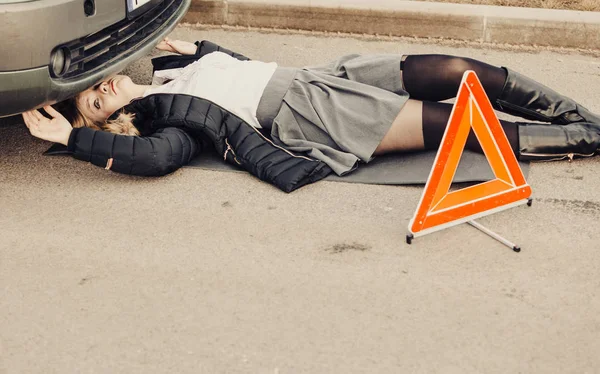 Woman, repairing broken car lying under it — Stock Photo, Image