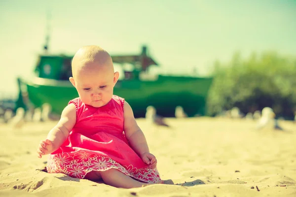 Pequeno bebê sentado e brincando na praia — Fotografia de Stock