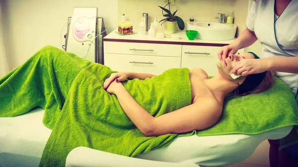 Beautician wiping off green mask on woman — Stock Photo, Image