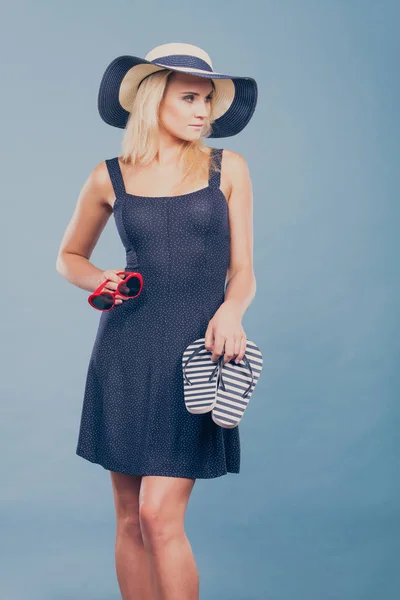 Mujer con vestido corto sosteniendo chanclas y gafas de sol —  Fotos de Stock