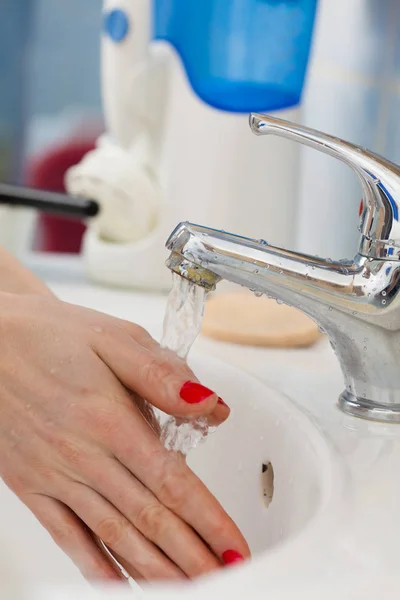 Mujer lavándose las manos bajo el agua corriente del grifo en el baño — Foto de Stock