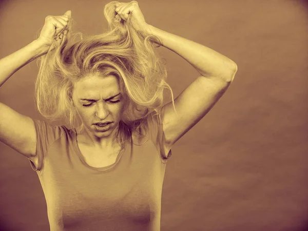 Frustrated woman holding her damaged blonde hair — Stock Photo, Image