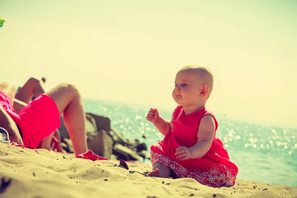 Pequeno bebê sentado e brincando na praia — Fotografia de Stock