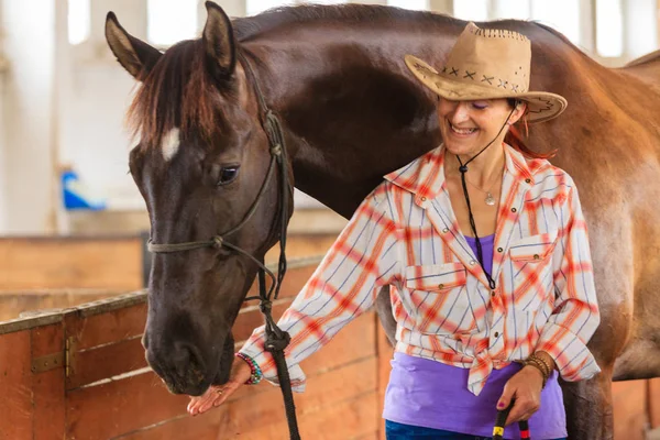 Cowgirl står bredvid brun häst vän — Stockfoto