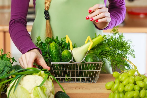 Mulher na cozinha com legumes segurando cesta de compras — Fotografia de Stock