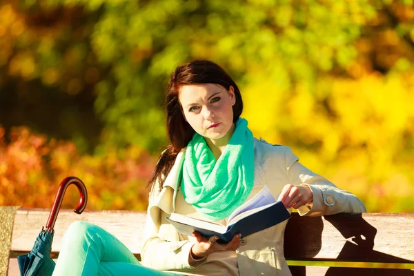 Жінка читає книгу, сидячи на лавці в парку — стокове фото