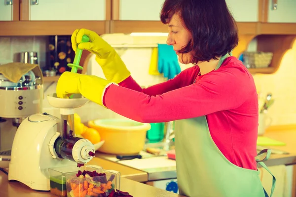 Vrouw maakt groentesappen in sapmachine — Stockfoto