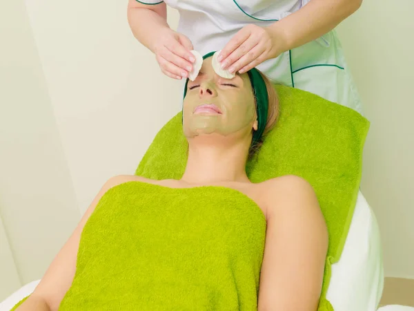 Kosmetička, otření zelenou masku na ženu — Stock fotografie