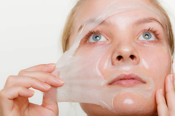 Kvinna att ta bort facial peel off mask. — Stockfoto