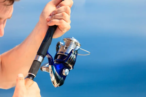Homme tenant une canne à pêche, bleu en arrière-plan — Photo