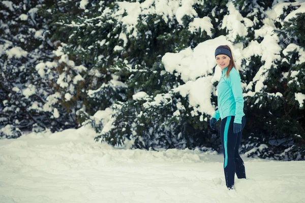 Standing girl wearing winter sportswear, trees background — Stock Photo, Image