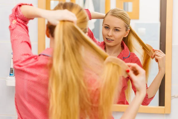 Vrouw kammen van haar lange haren in de badkamer — Stockfoto