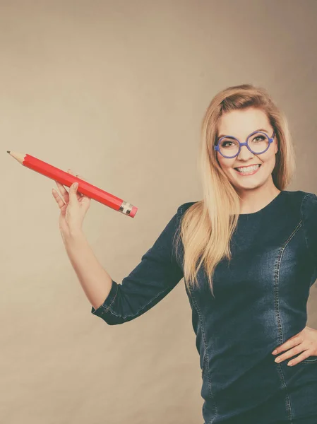 Mujer sonriente sostiene un lápiz grande en la mano — Foto de Stock