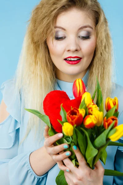 Mulher segura tulipas e coração vermelho — Fotografia de Stock