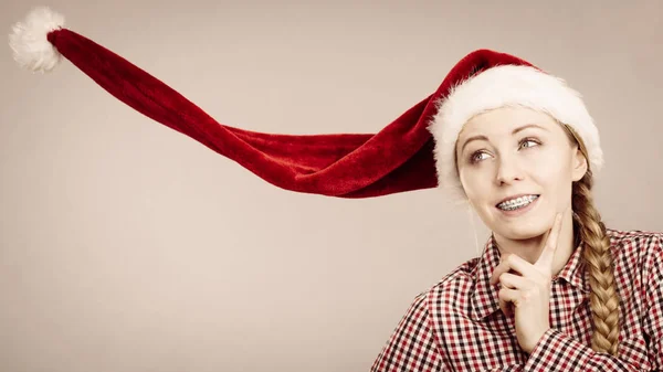 Menina positiva vestindo soprando chapéu de Papai Noel — Fotografia de Stock