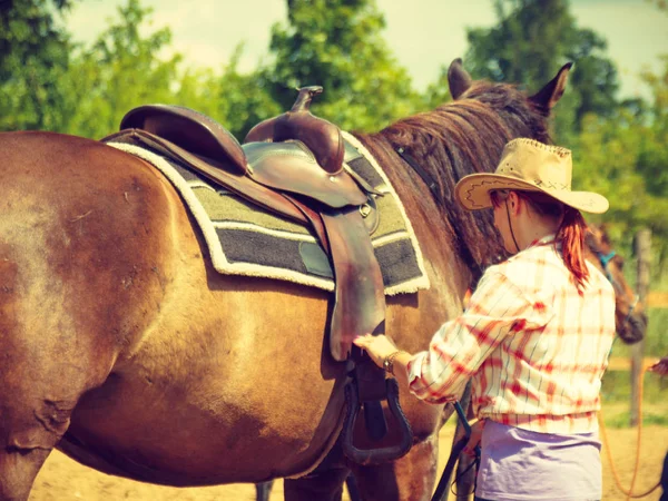 Cowgirl, příprava koně pro jízdu na venkově — Stock fotografie