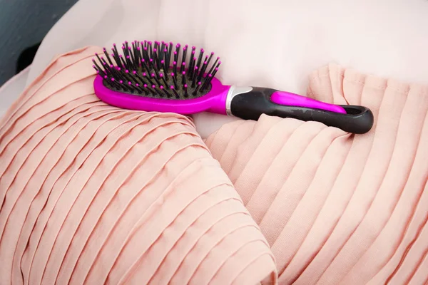 Schwarze und lila Haarbürste auf rosa Kissen — Stockfoto