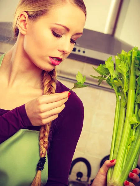 Donna in cucina tiene sedano verde — Foto Stock