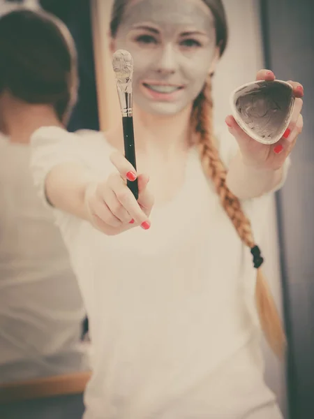 女孩抱着粘土泥面膜和画笔。皮肤护理. — 图库照片