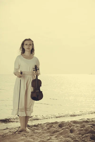Mulher na praia perto do mar segurando violino — Fotografia de Stock