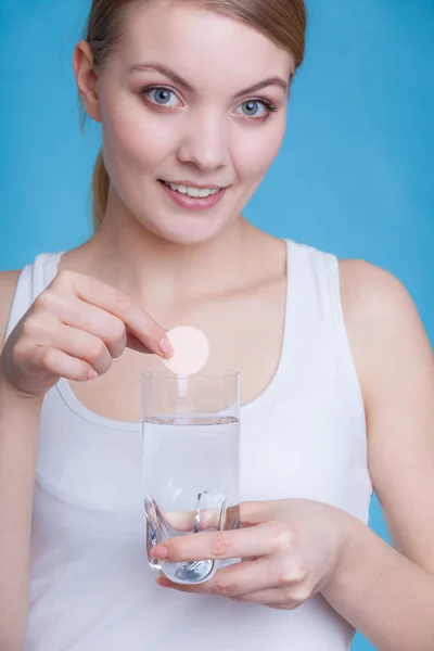 Женщина, держащая стакан с водой и шипучей таблеткой — стоковое фото