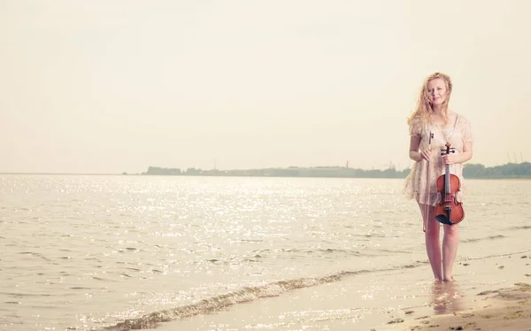 Donna sulla spiaggia vicino al mare che tiene violino — Foto Stock