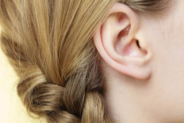 Gros plan sur l'oreille féminine et les cheveux tressés — Photo