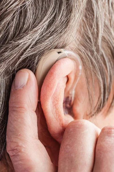 Closeup senior woman using hearing aid — Stock Photo, Image