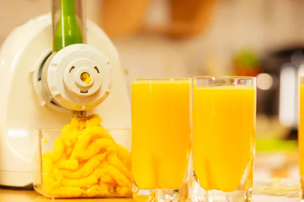 Hacer jugo de naranja en la máquina de juicer en la cocina —  Fotos de Stock