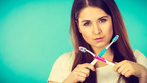 Vrouw bedrijf twee tandenborstels gekruist — Stockfoto