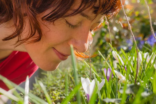 Woman smelling white crosus on grass — Stock Photo, Image