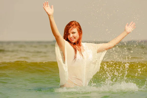 Rödhårig kvinna spelar i vatten under sommaren — Stockfoto