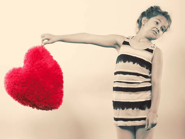 Liten flicka unge med rött hjärta form kudde. — Stockfoto