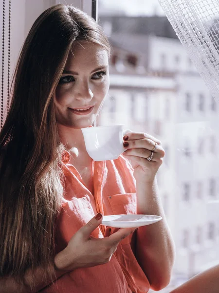 Nő keres ablakon, kellemes kávé, tea — Stock Fotó