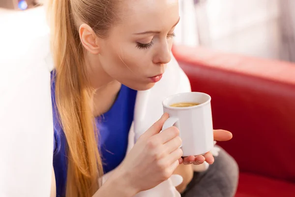 Mujer acostada en un sofá bajo una manta bebiendo té — Foto de Stock