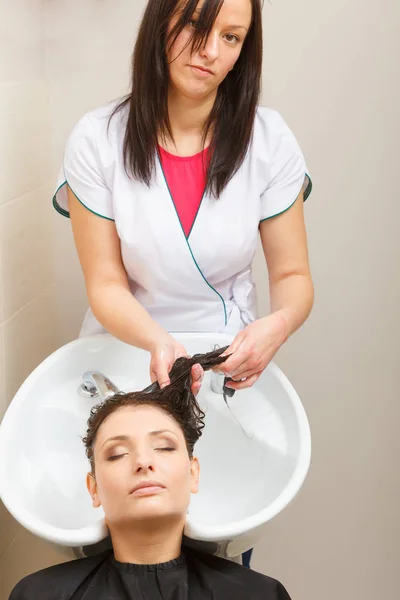 Kadeřník, mýt vlasy zákazníků žena — Stock fotografie
