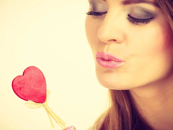 Flirty woman holding red wooden heart on stick — Stock Photo, Image