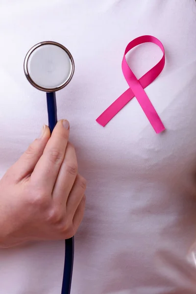 Pink ribbon and stethoscope on female chest — Stock Photo, Image