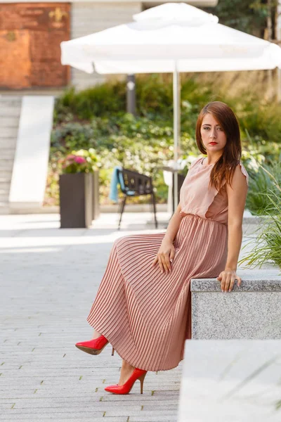 Vrouw in lange jurk zittend op stad straat — Stockfoto